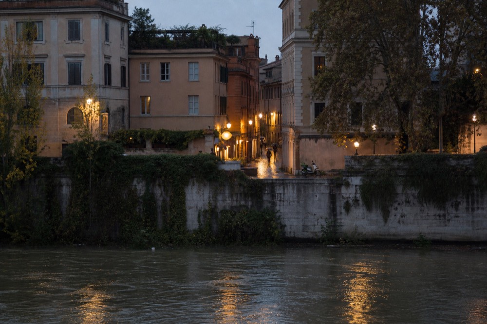 An evening Trastevere alley with lit counters and people walking