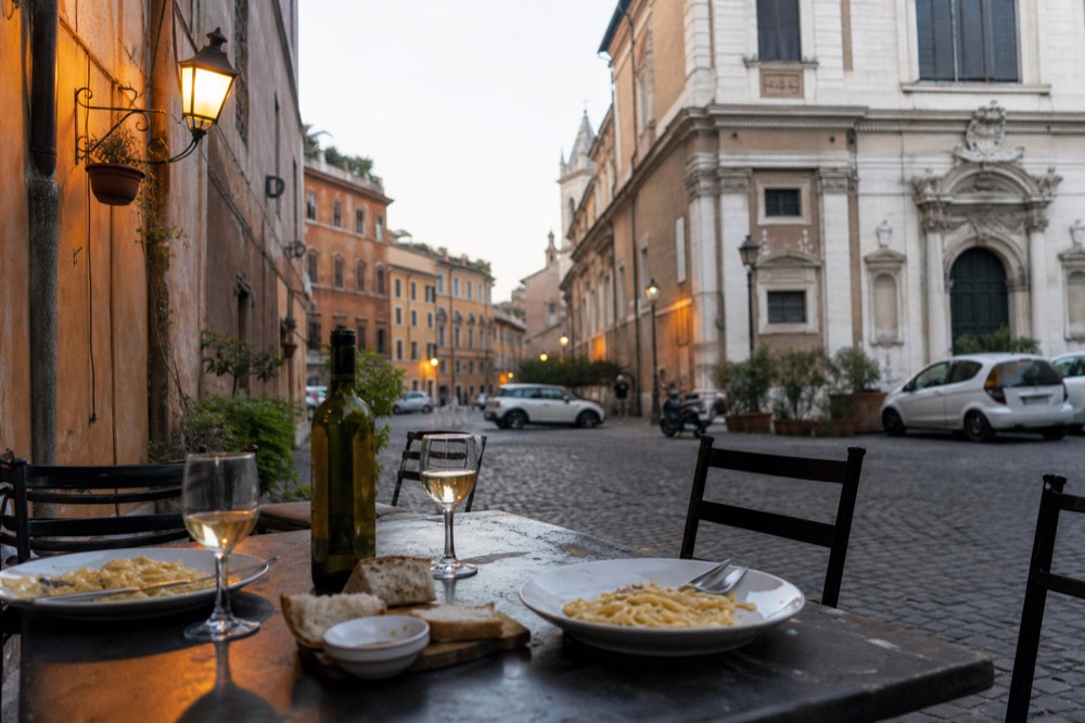 A table set with plates of fresh pasta, glasses of white wine and bread
