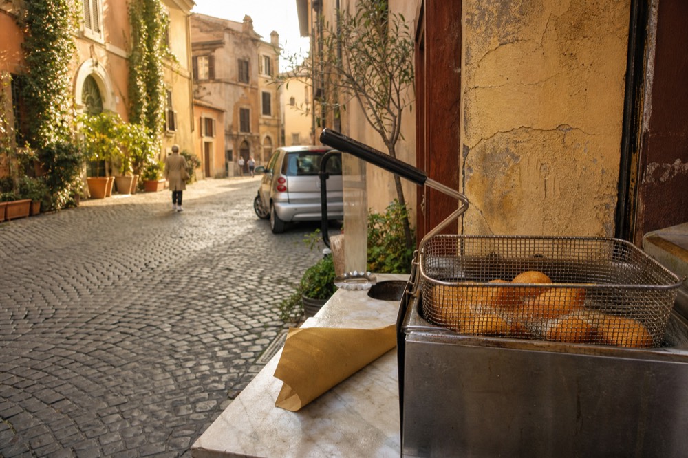 Rice croquettes frying in a basket of hot oil at a street food counter