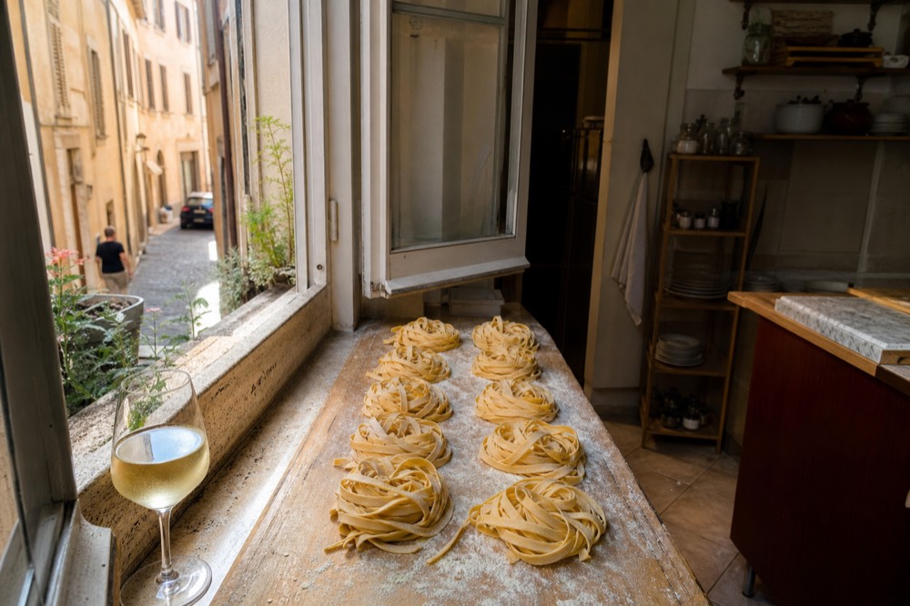 Fresh fettuccine nests dusted with flour on a wooden board in a Rome kitchen