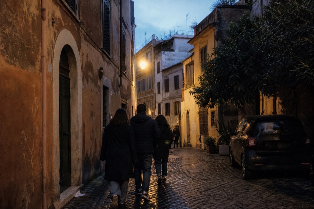 A small group on an evening food walk through a lantern-lit Roman street