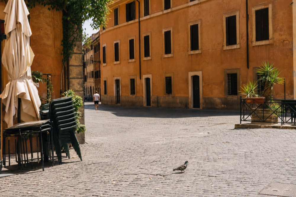 Shaded terrace with parasols closed and chairs stacked in a Roman square