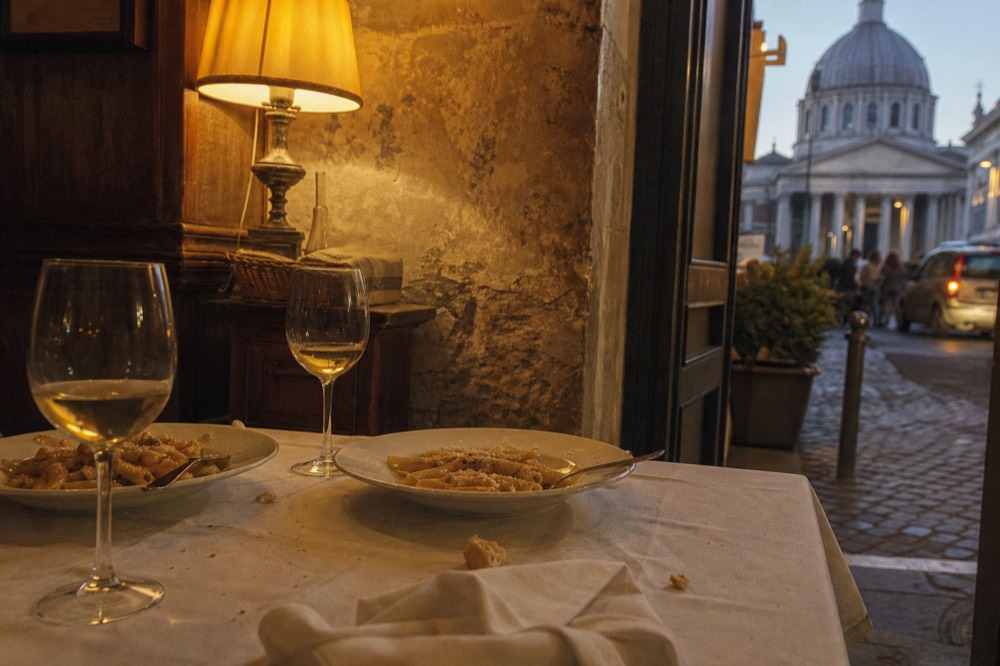 A trattoria table set with wine and pasta in a Roman dining room